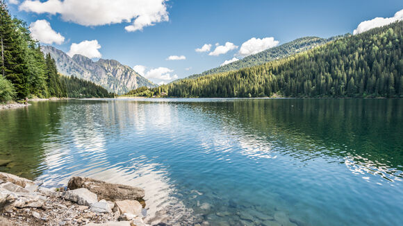 Wunderschöner blau/grüner Arnensee umgeben von Bäumen und Steinen.